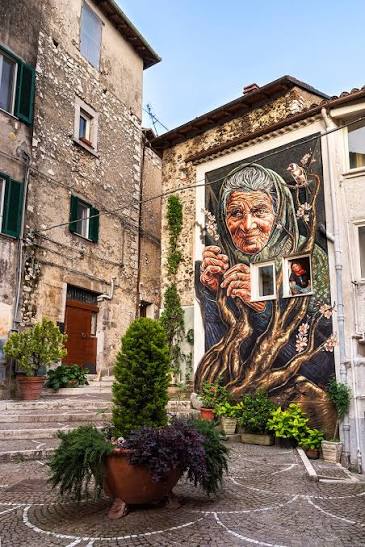 Mural of an elderly woman's face on a facade in Fiuggi's old town