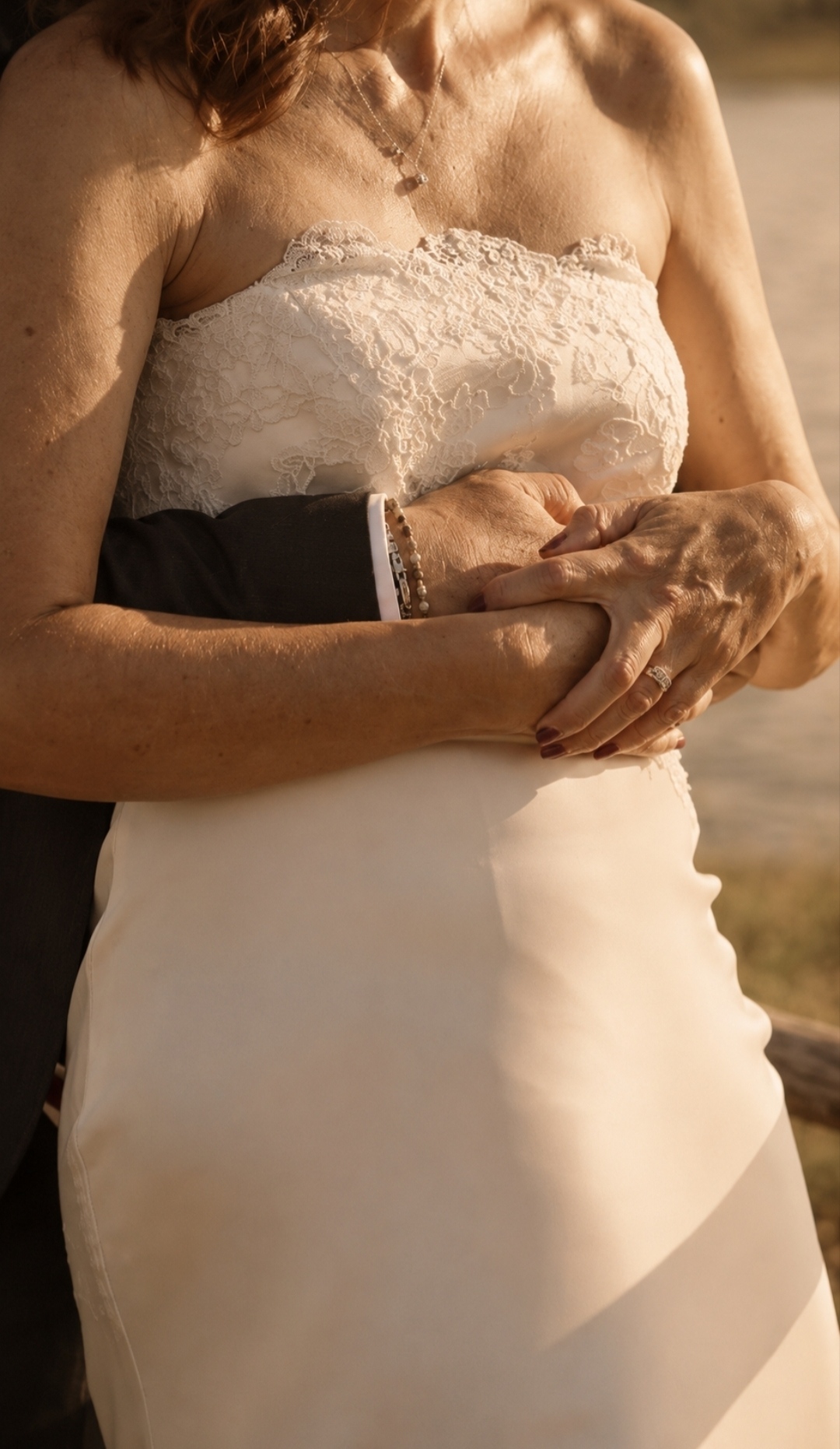 Detail of the couple's embrace, lace dress and warm light