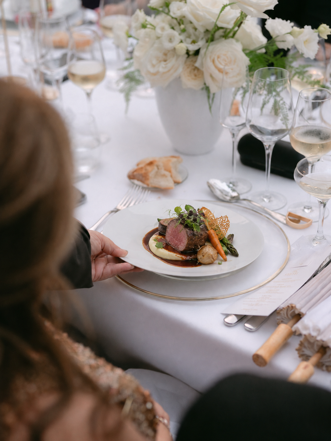 A wedding menu dish served at the table during a reception at Villa Sant'Erasmo, with white flowers, glasses and bread