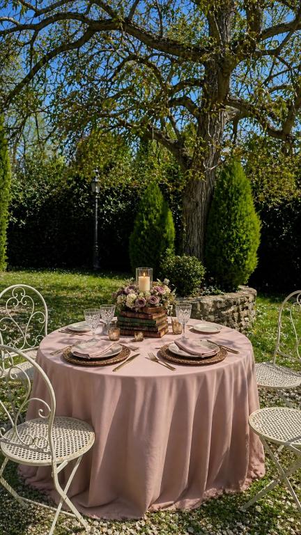 Table for two with a pink mise en place beneath a large tree in the garden
