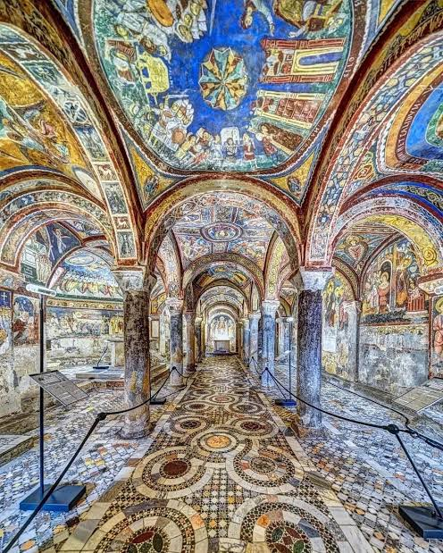 Interior of the Crypt of San Magno in Anagni with frescoed vaults, stone columns and Cosmatesque flooring