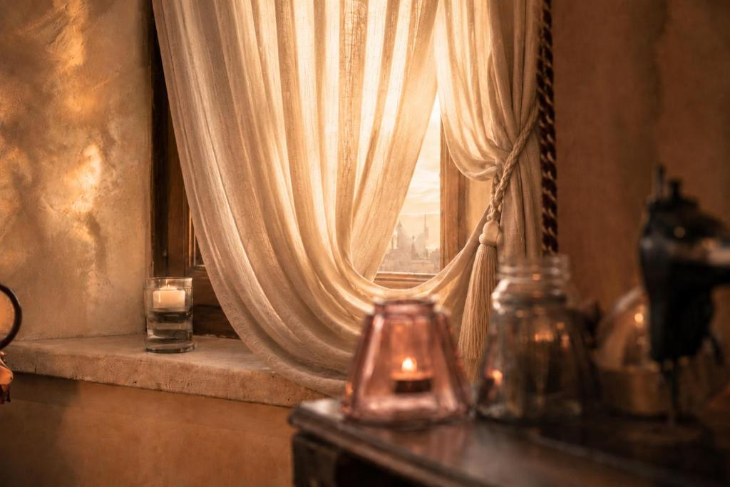 Sheer-curtained window and lit candles inside Villa Sant'Erasmo