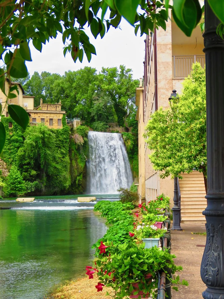 The Cascata Grande of Isola del Liri seen from the riverside path, among stone houses and flowers along the promenade