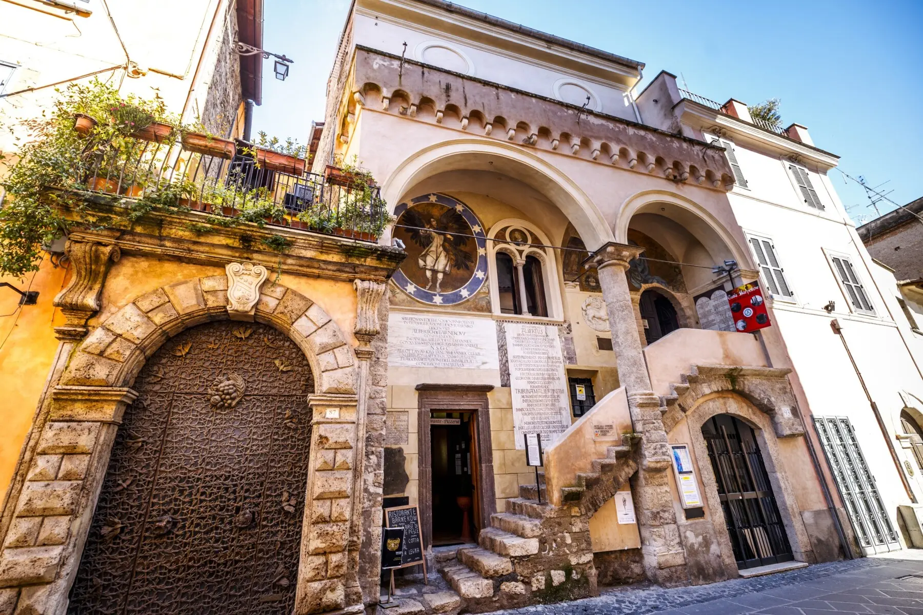 The facade of Casa Barnekow in Anagni with its two-arched loggia, frescoes of angels on a starry background, Latin inscriptions and stone staircase