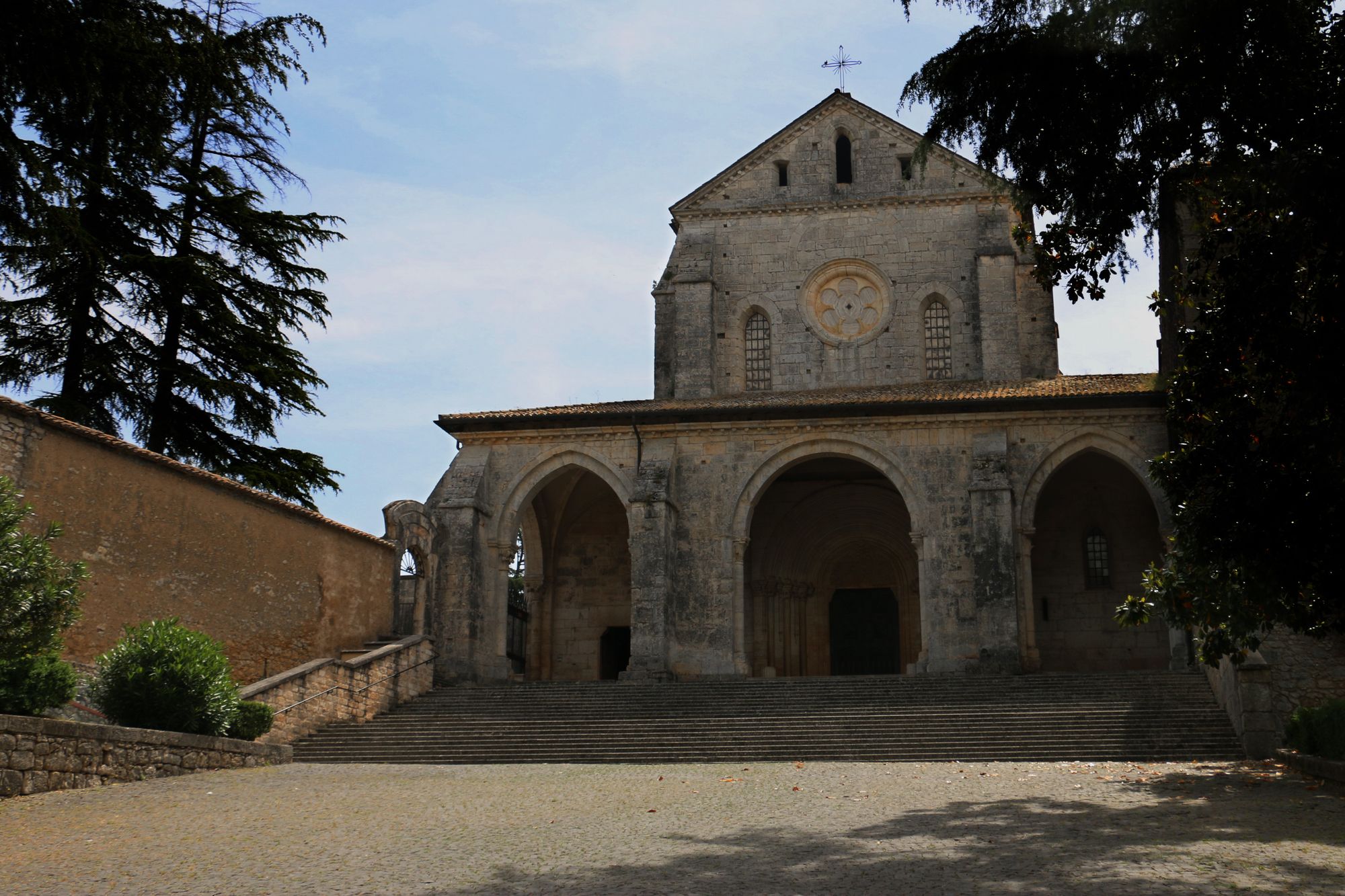 The Gothic-Cistercian facade of Casamari Abbey seen at an angle, with the stone path leading to the portal