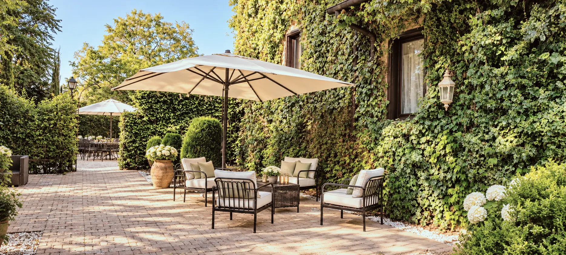 Outdoor lounge in the garden of Villa Sant'Erasmo, with parasol, seating areas and ivy-clad facade