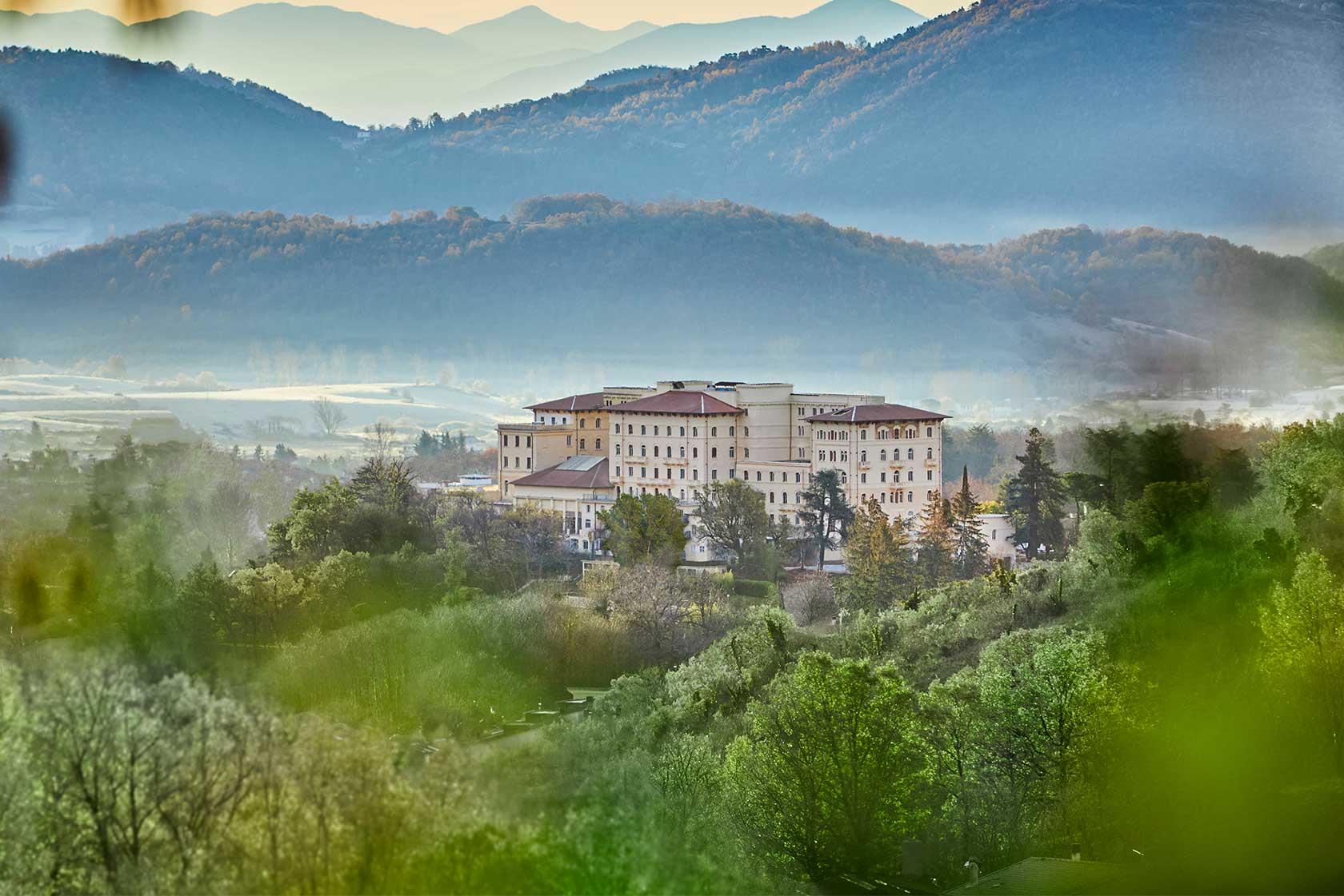 The thermal building of Fiuggi Fonti surrounded by greenery, with the valley's mountains beyond